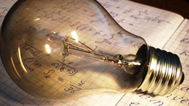 Lightbulb sitting on Notebook with Writing.